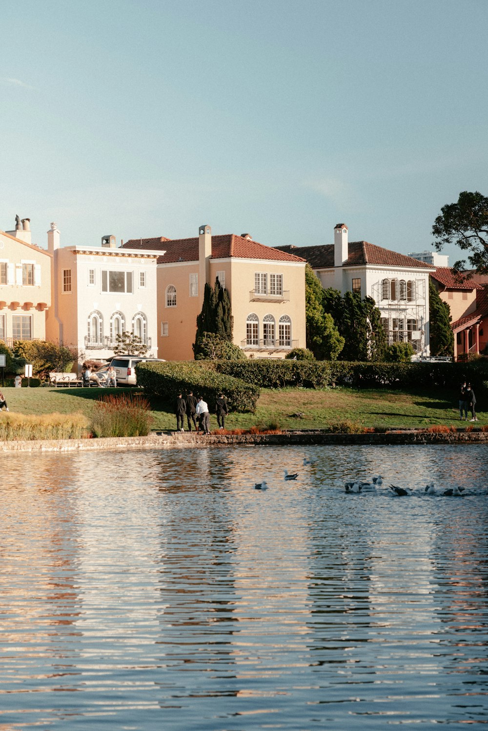 a large house sitting on top of a lush green hillside next to a lake