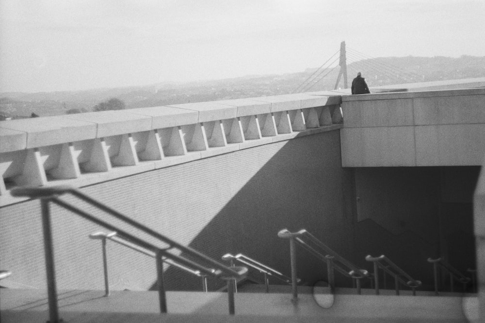 a black and white photo of a person sitting on top of a building