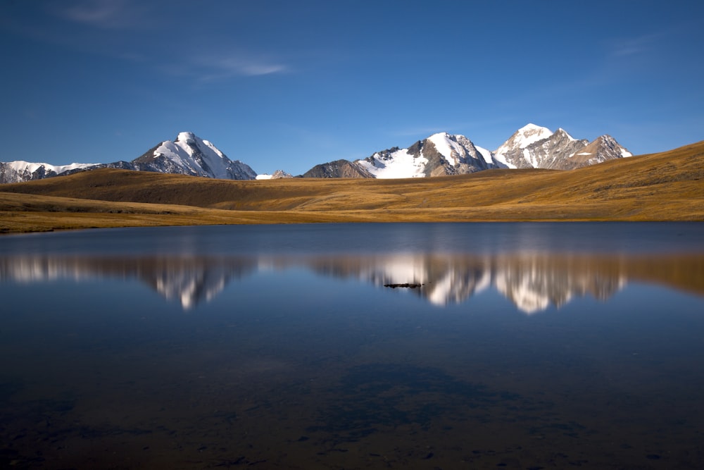 a mountain range is reflected in the still water of a lake