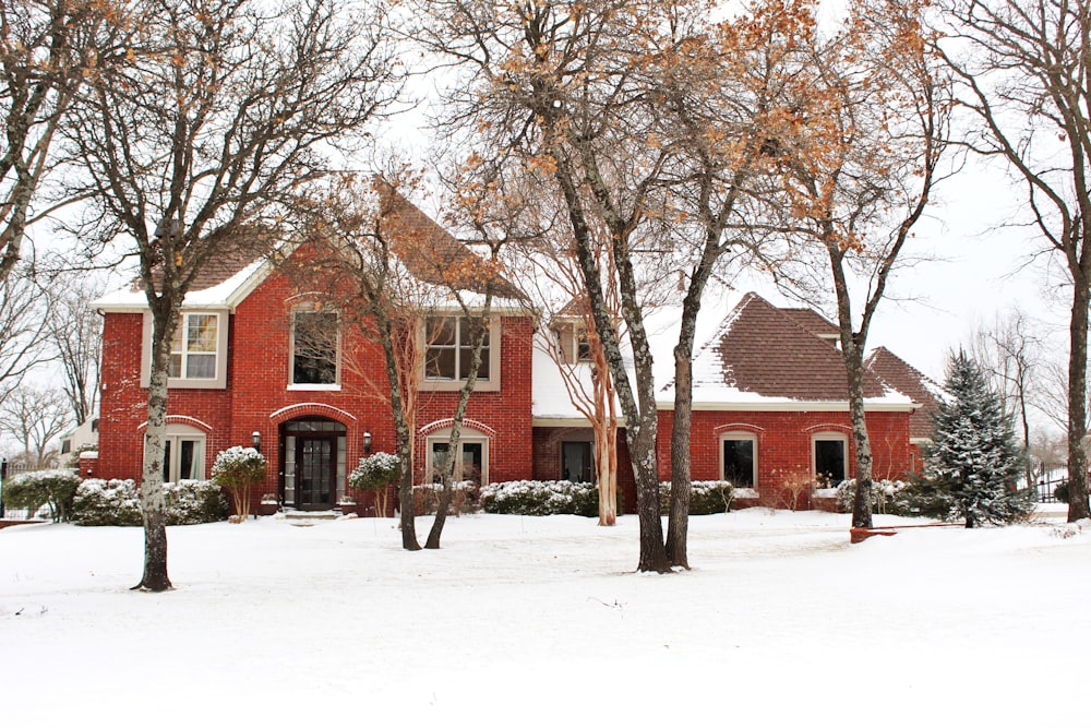 a red brick house surrounded by trees and snow