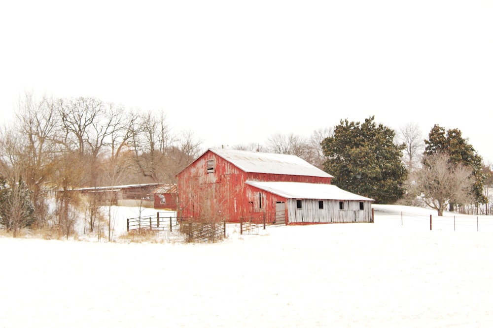 a red barn in the middle of a snowy field