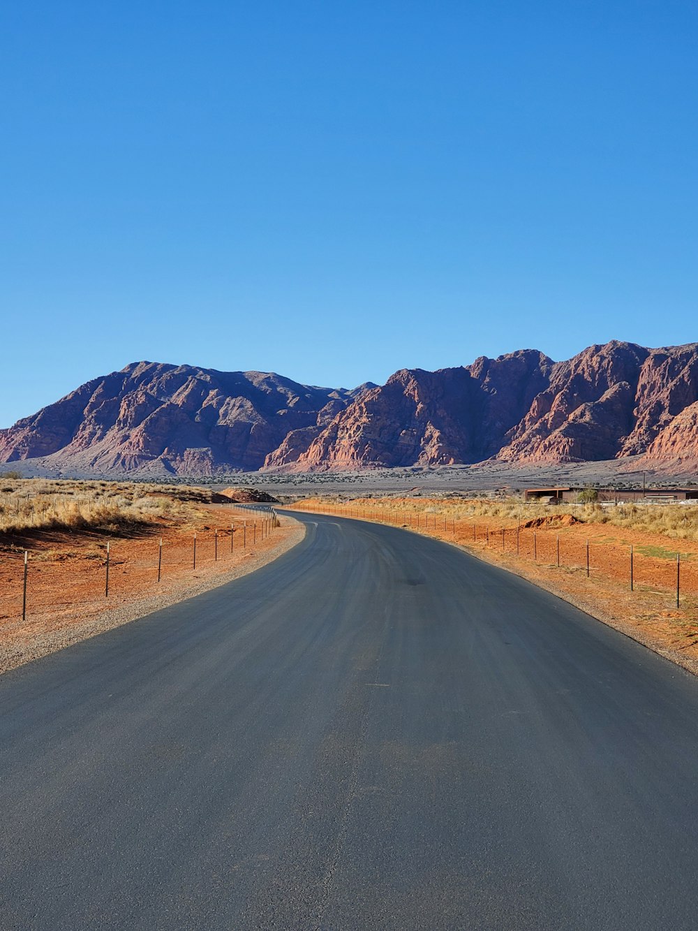 a road in the middle of a desert with mountains in the background