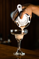 a person pours a drink into a martini glass