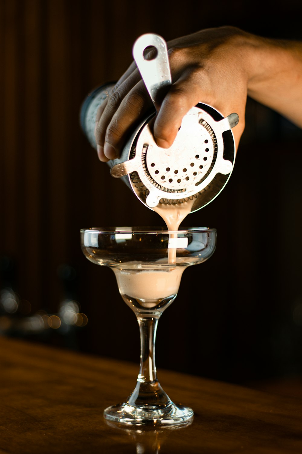 a person pours a drink into a martini glass