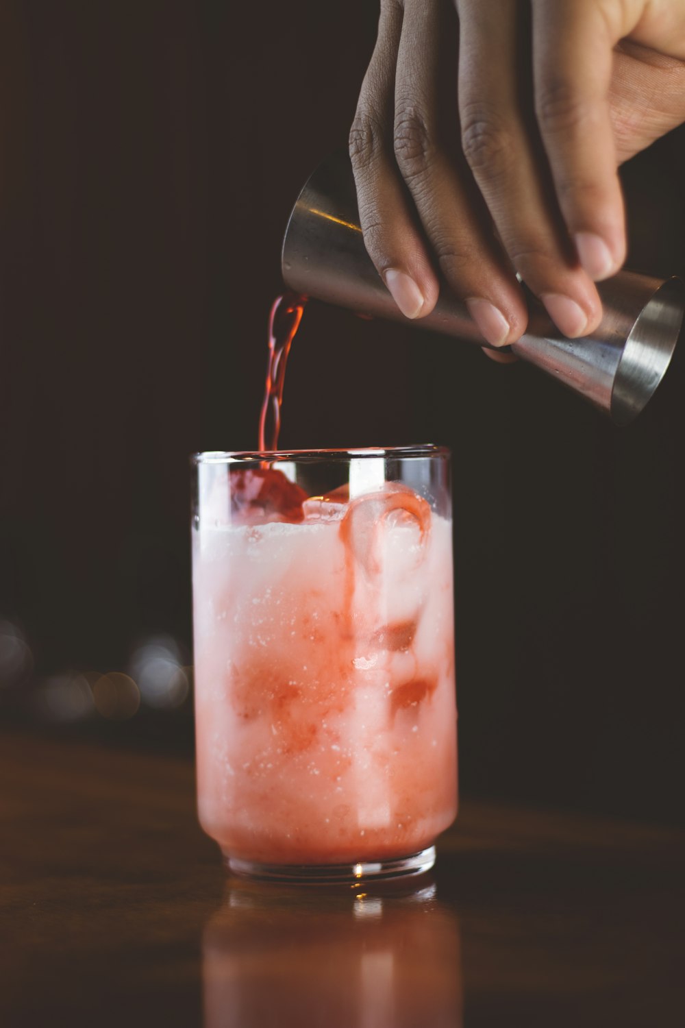 a person pouring a drink into a glass