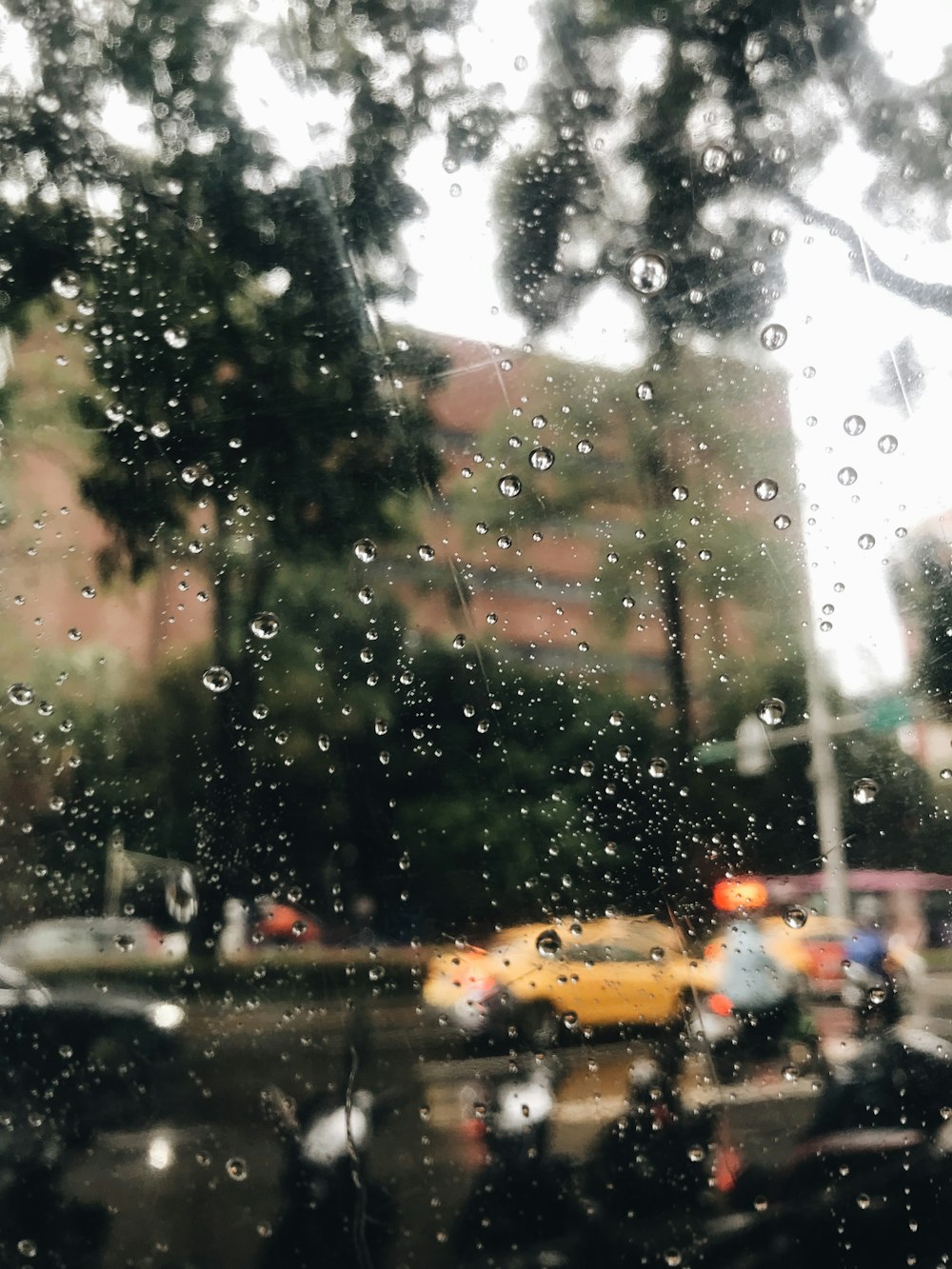 une vue d’une rue à travers une fenêtre couverte de pluie