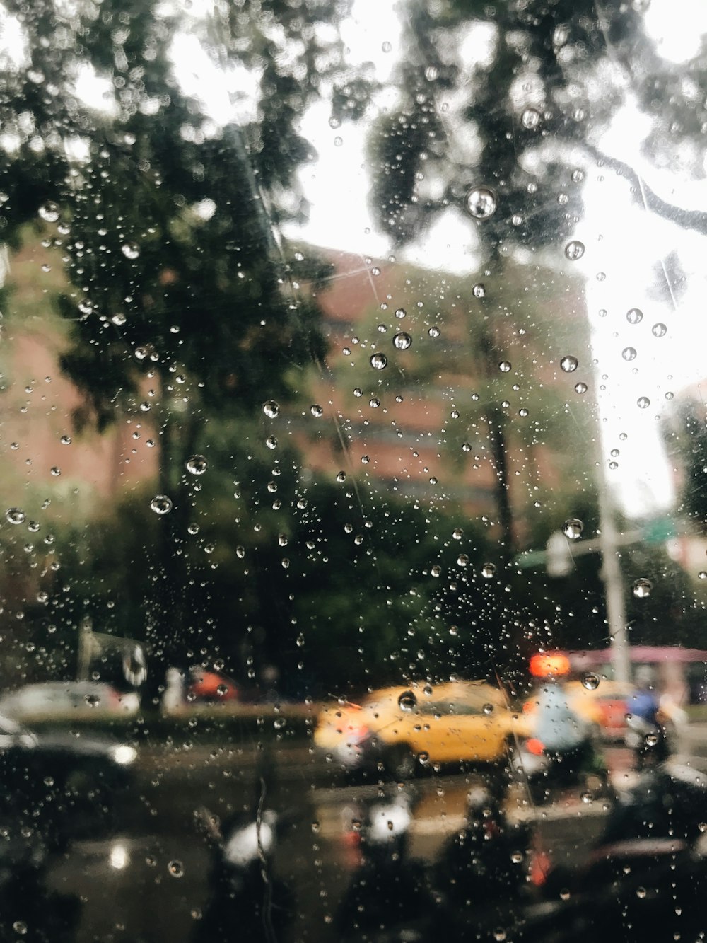 uma vista de uma rua através de uma janela coberta de chuva