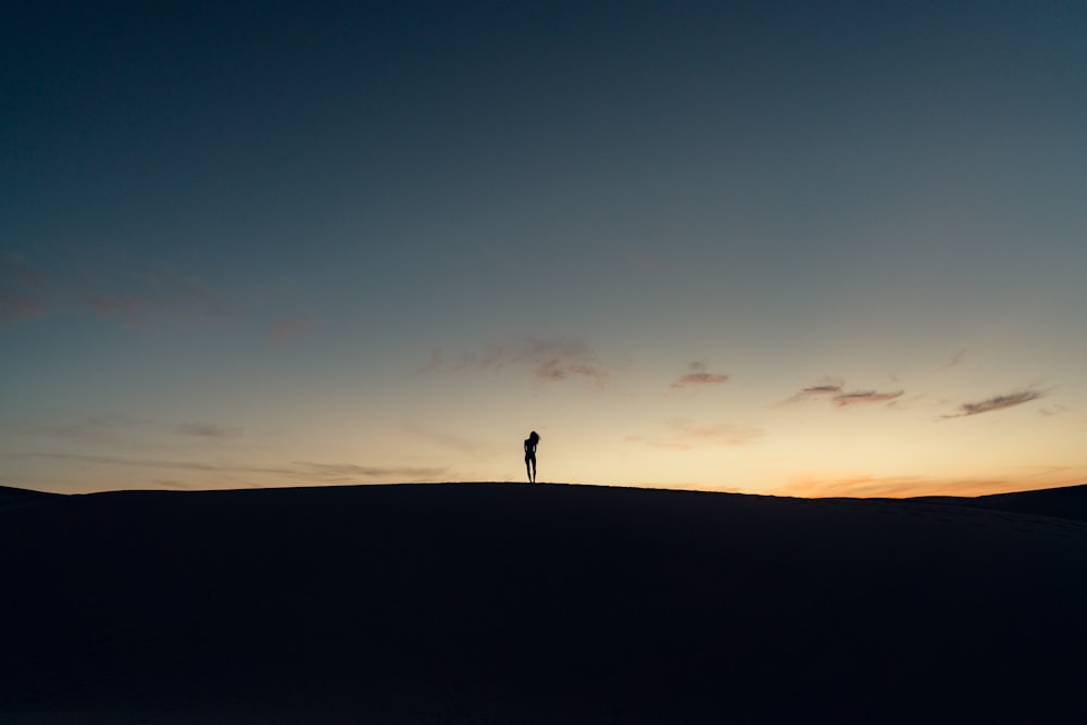 a person standing on top of a hill at sunset