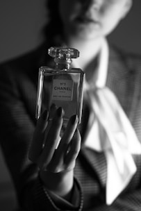 a woman in a suit holding a bottle of chanel