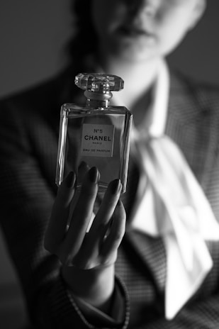 a woman in a suit holding a bottle of chanel