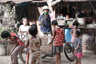 a group of young children standing around a bicycle