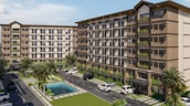 A modern apartment complex featuring two multi-story buildings with large windows and balconies. The complex is surrounded by landscaped areas with palm trees and a small pool in the center. Several parked vehicles are situated along the paved driveway that runs between the buildings.