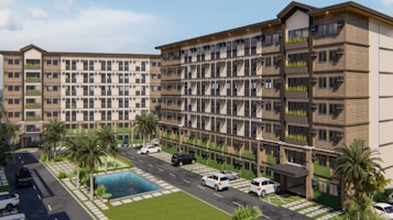 A modern apartment complex featuring two multi-story buildings with large windows and balconies. The complex is surrounded by landscaped areas with palm trees and a small pool in the center. Several parked vehicles are situated along the paved driveway that runs between the buildings.