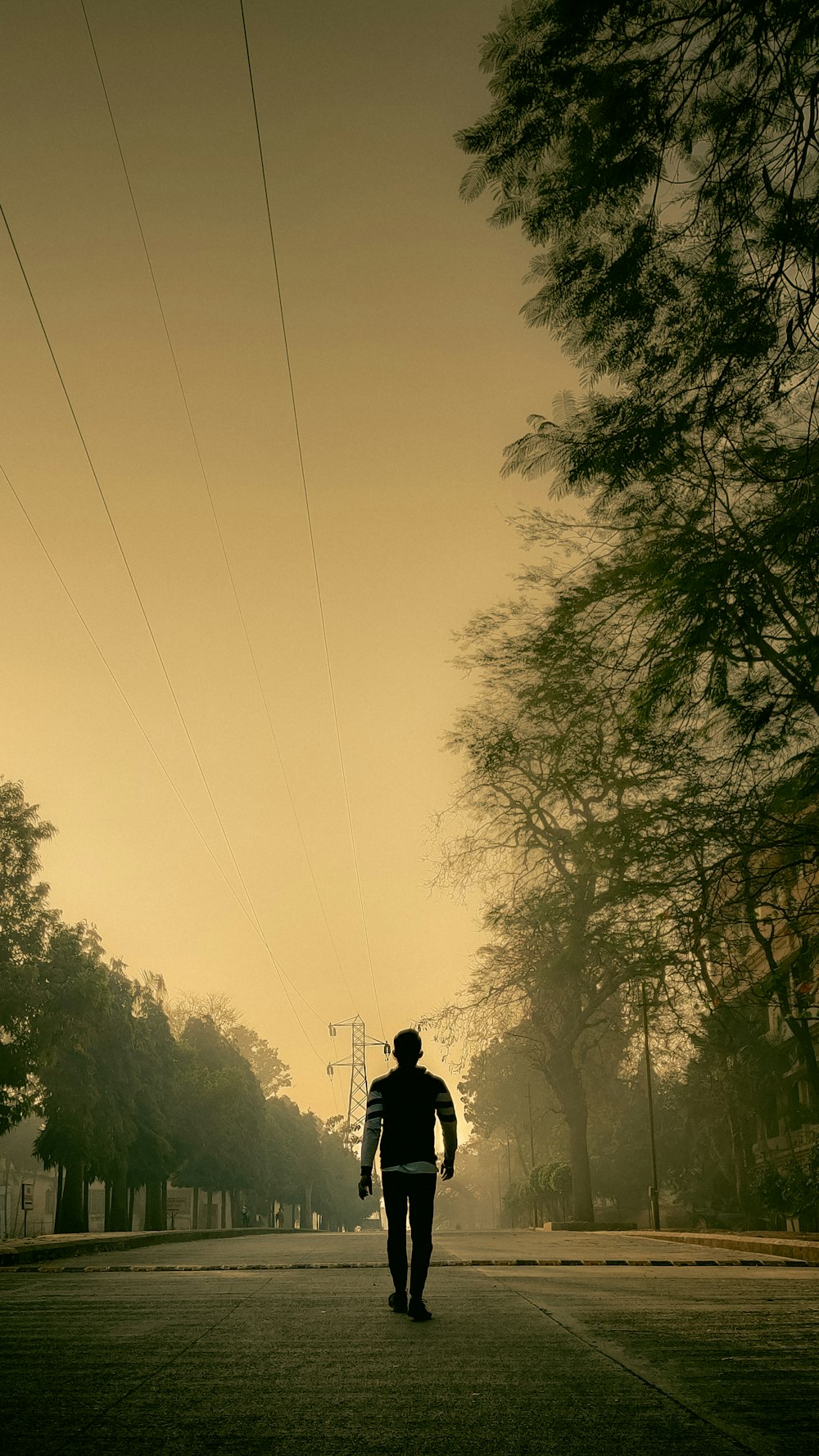 a man walking down a street with power lines above him