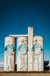 two large silos with a mural of two men in cowboy hats