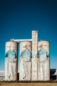 two large silos with a mural of two men in cowboy hats