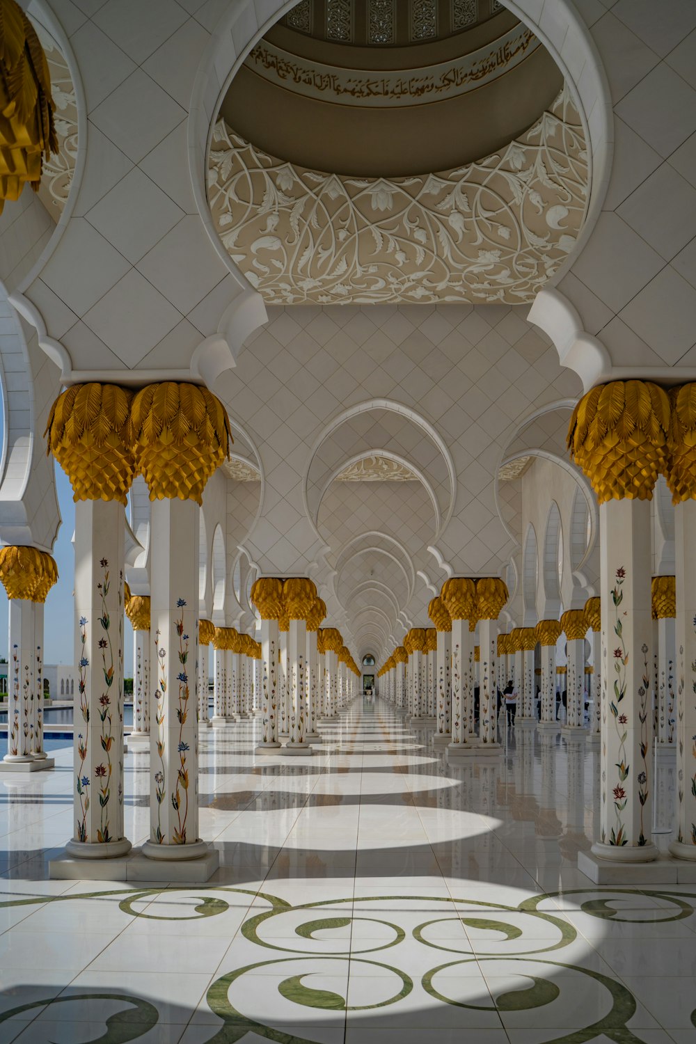 a long hallway with columns and yellow flowers
