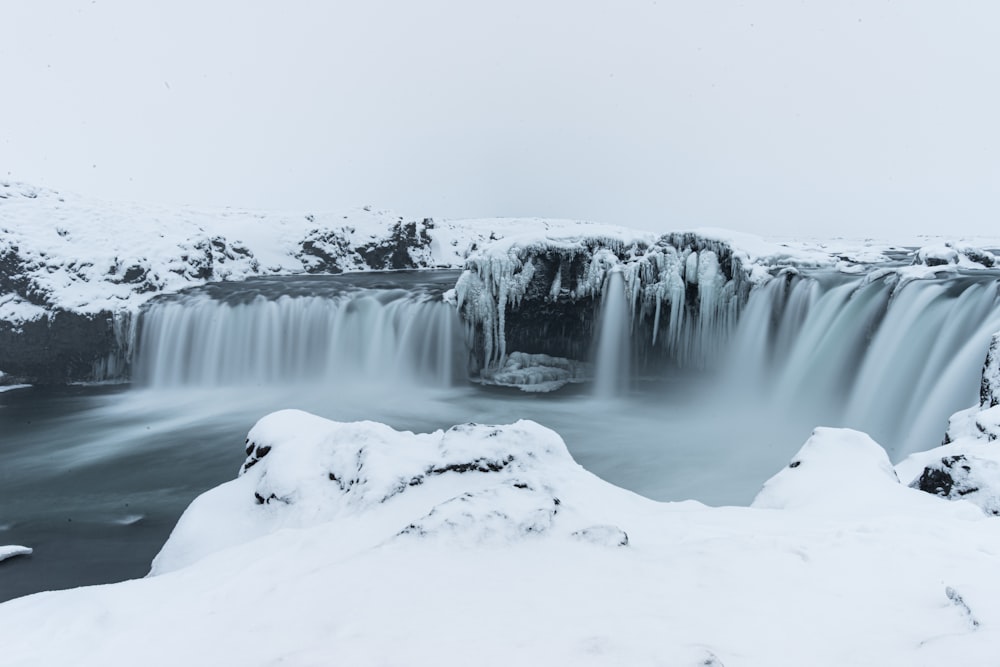 a frozen waterfall with snow on the ground