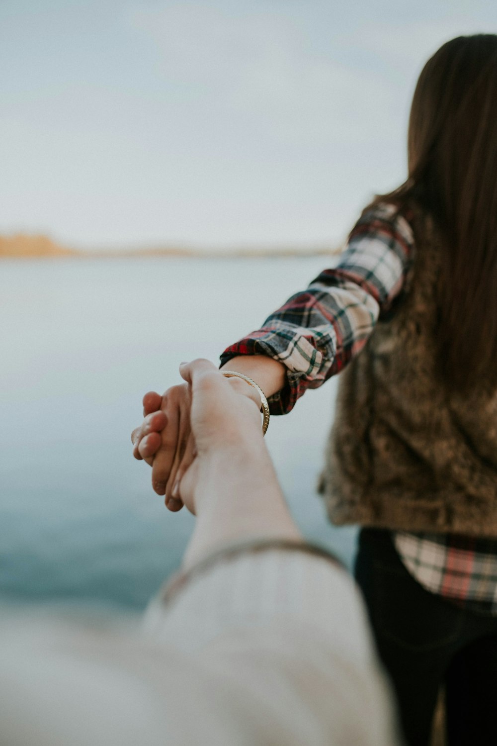 a couple holding hands while standing next to a body of water