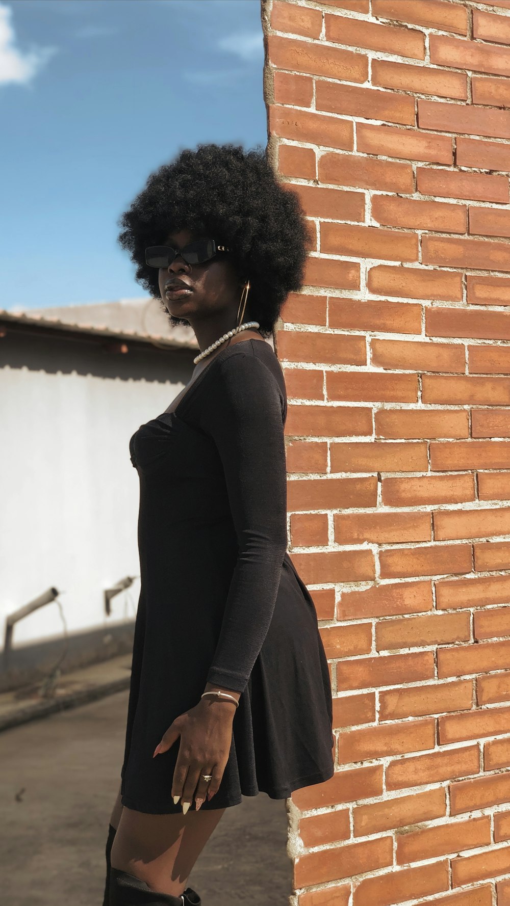 a woman standing next to a brick wall