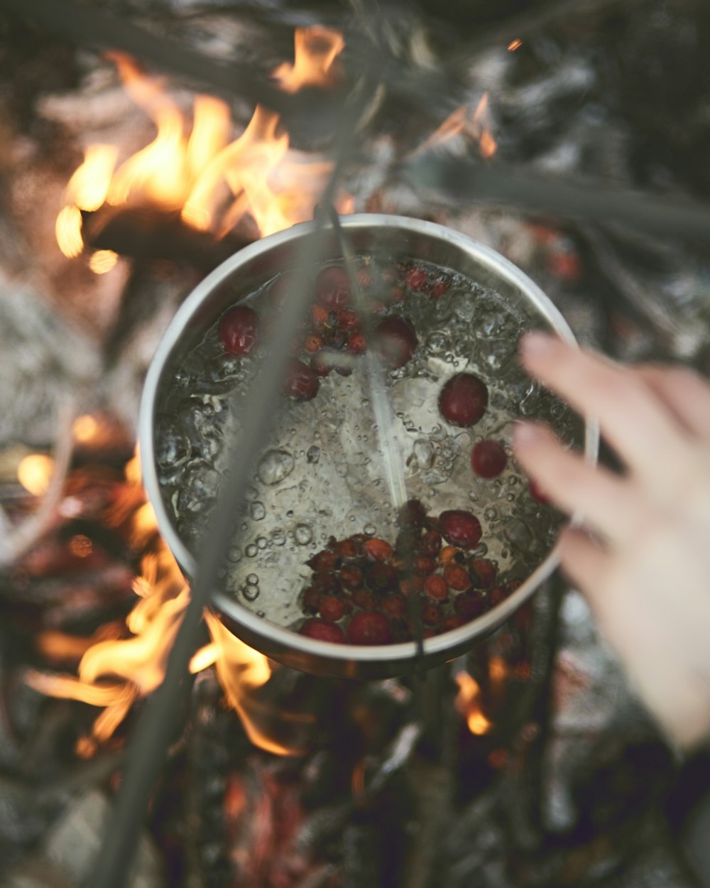 a person stirring a pot of food over a fire