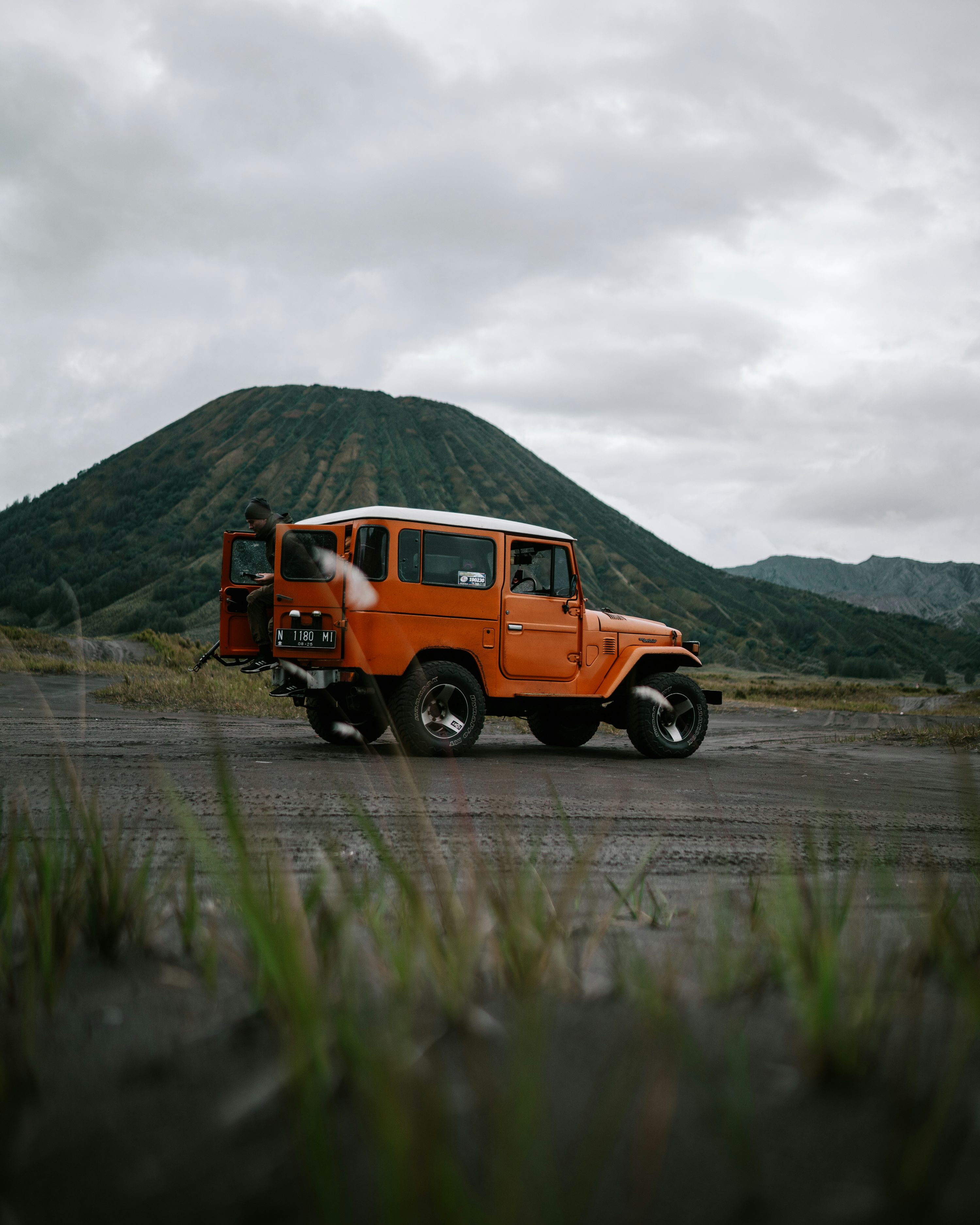 an orange jeep is parked in front of a mountain