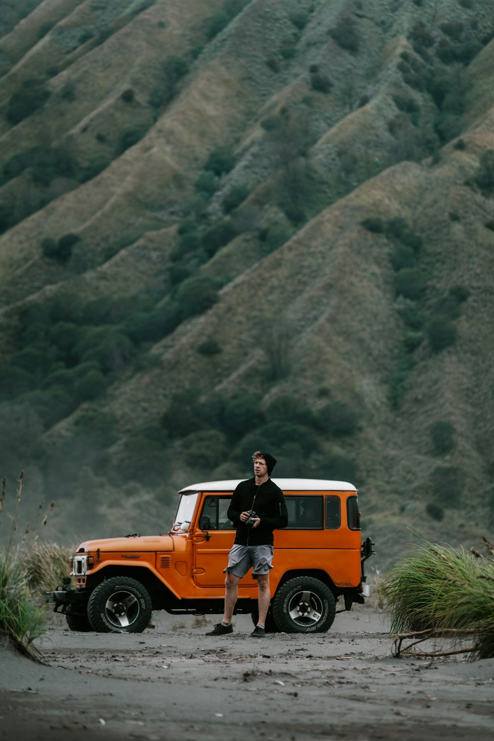 a man standing next to an orange jeep