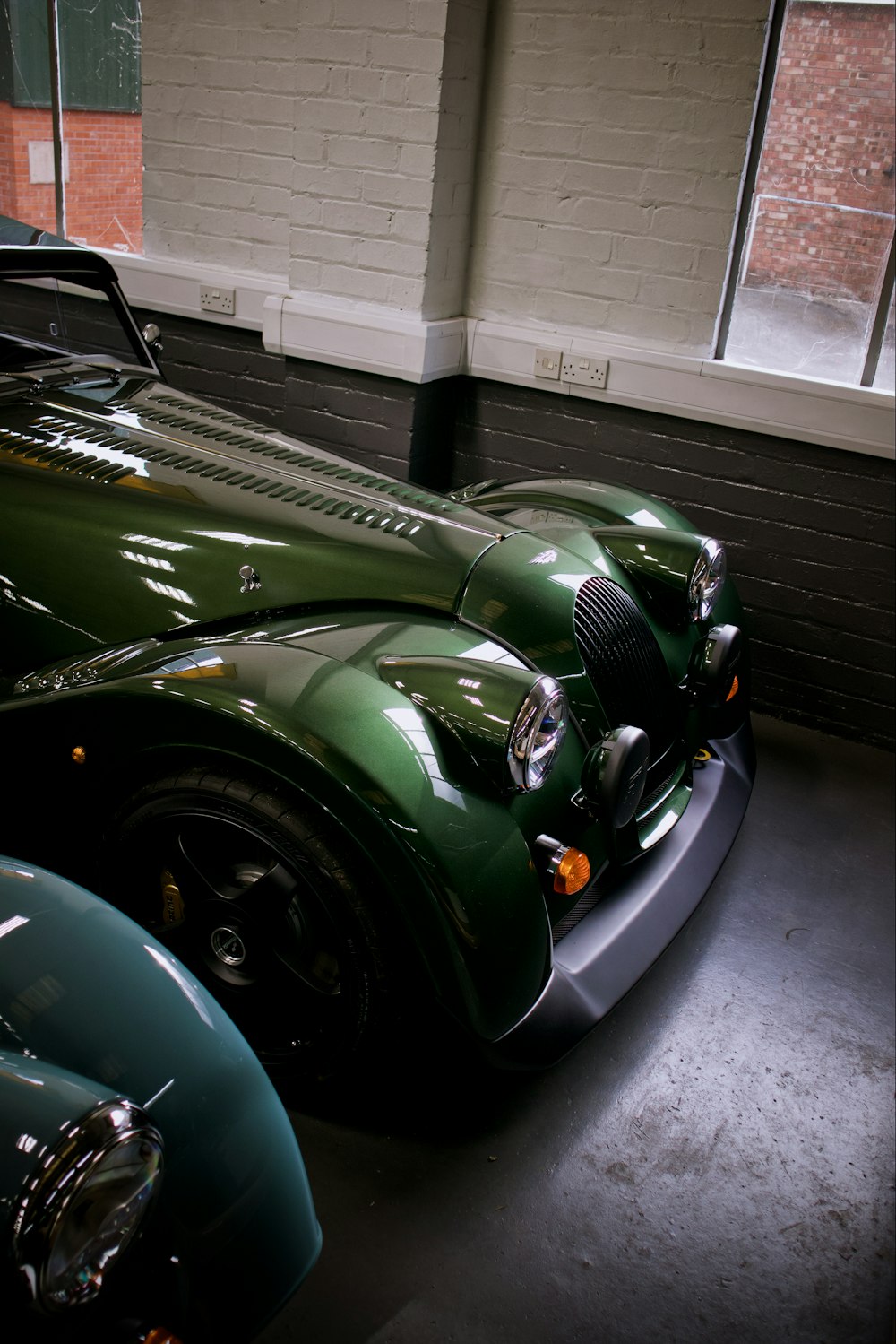 a green car parked in a garage next to another car