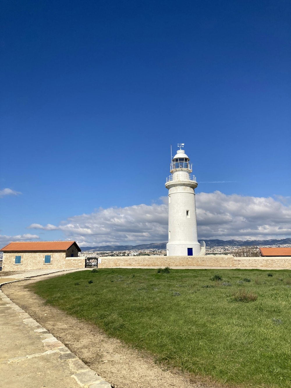 a white lighthouse sitting on top of a lush green field