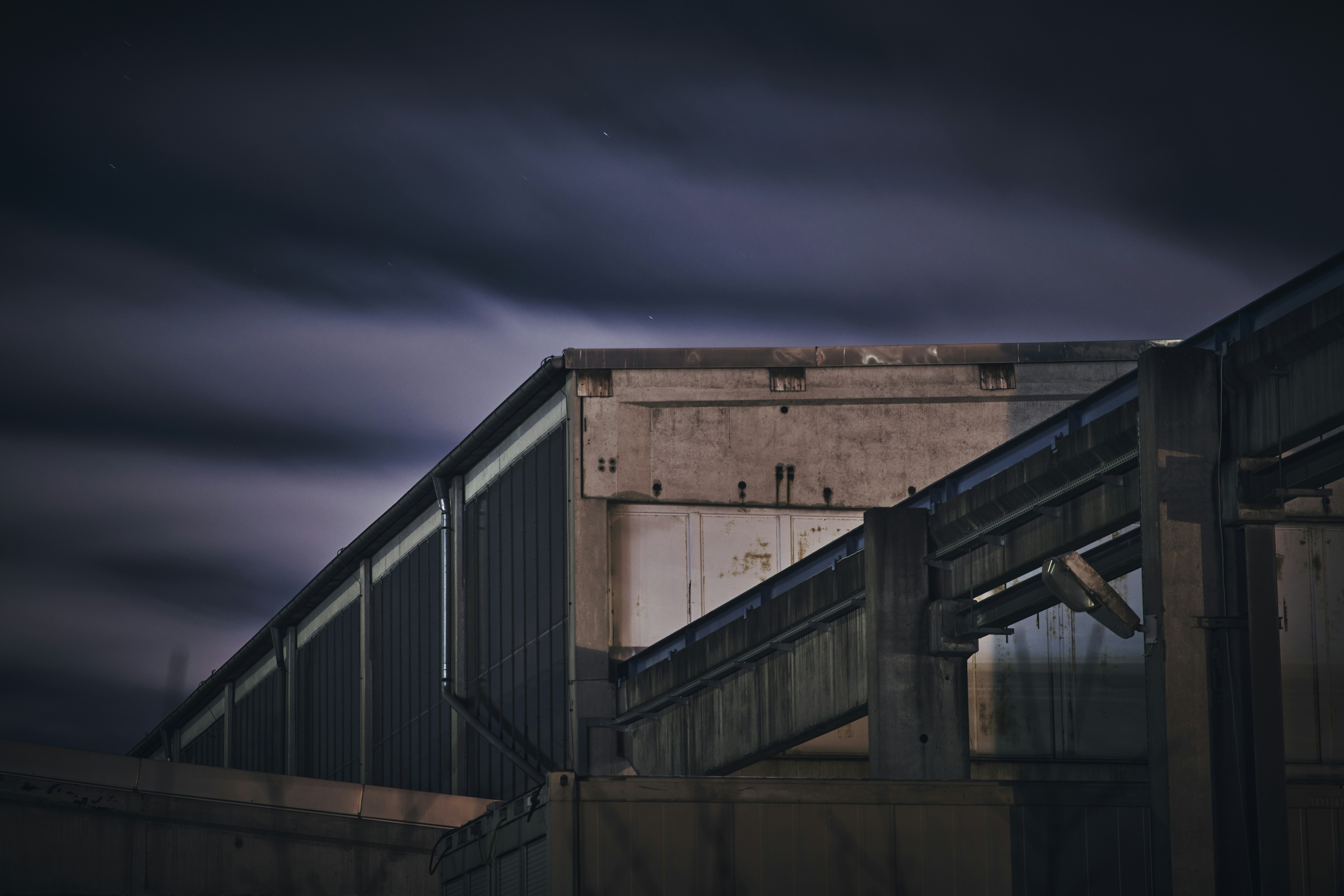 Modern industrial warehouse under construction, steel frame and concrete floor, overcast sky, dark atmospheric industrial setting