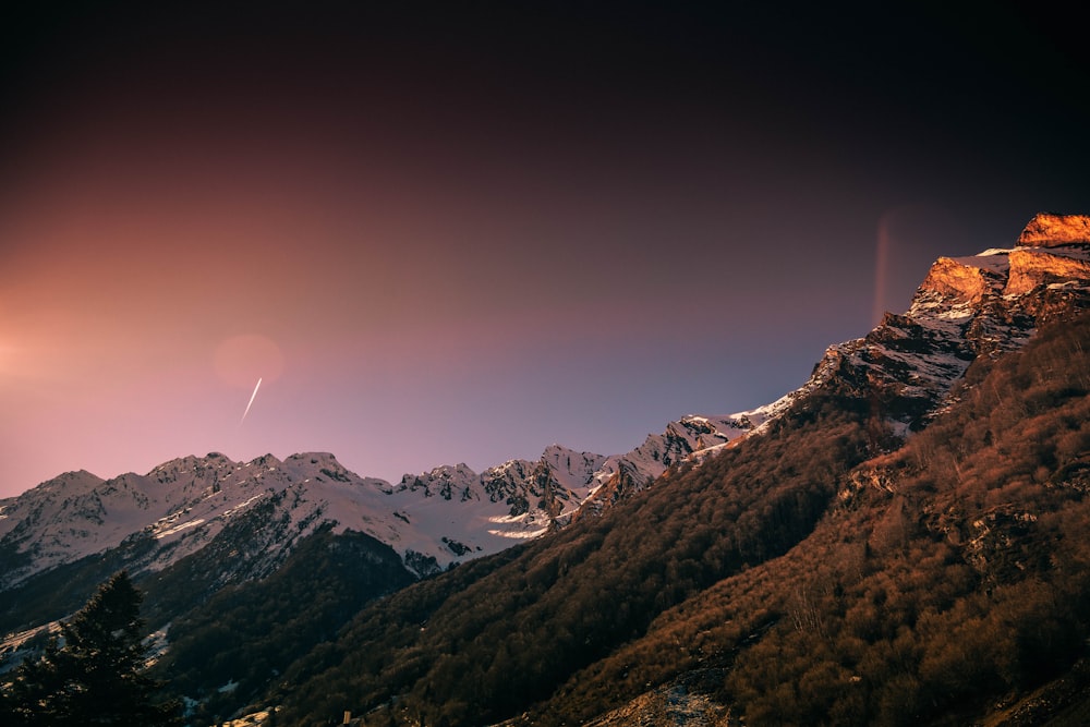 a view of a mountain with a plane flying in the sky