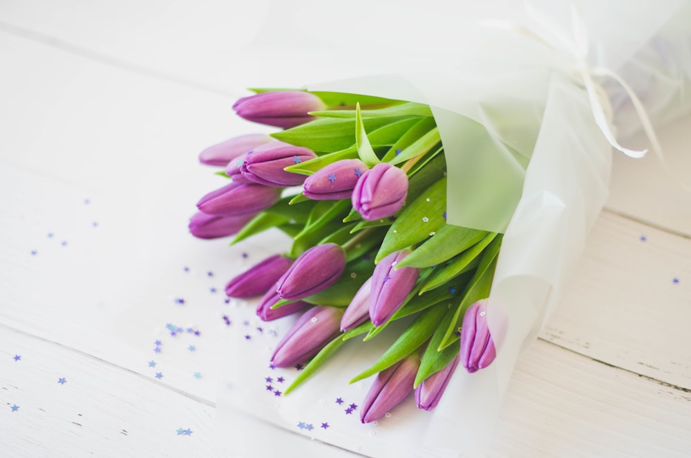 a bouquet of purple tulips wrapped in white paper