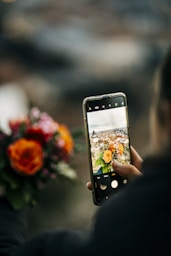 a person taking a picture of a vase with flowers