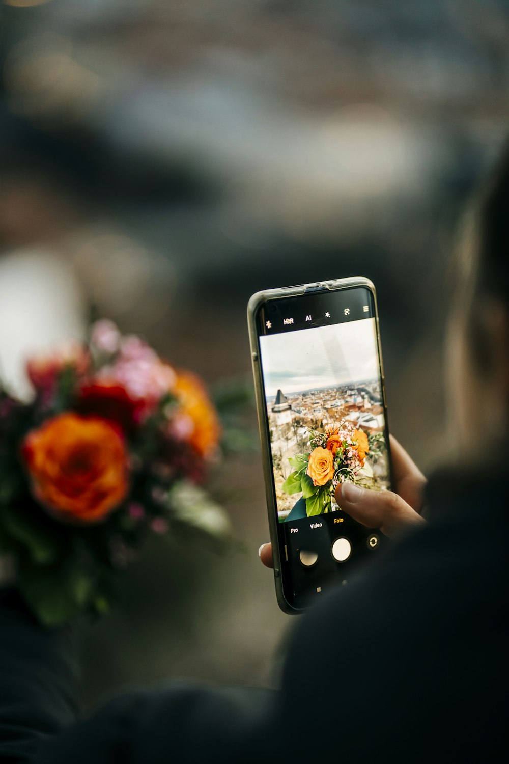a person taking a picture of a vase with flowers