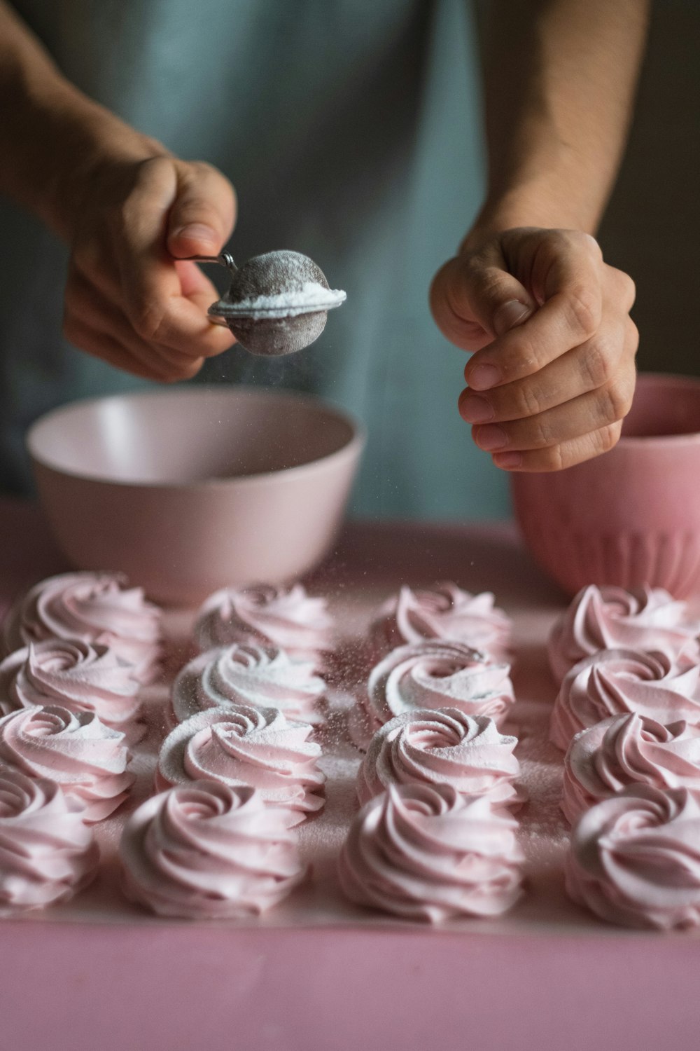 a person scooping icing from a spoon into a bowl