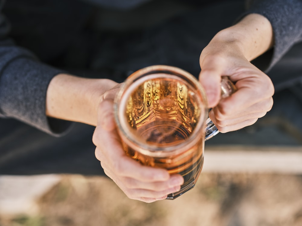 a person holding a glass of beer in their hands