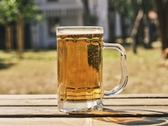 a glass of beer sitting on top of a wooden table