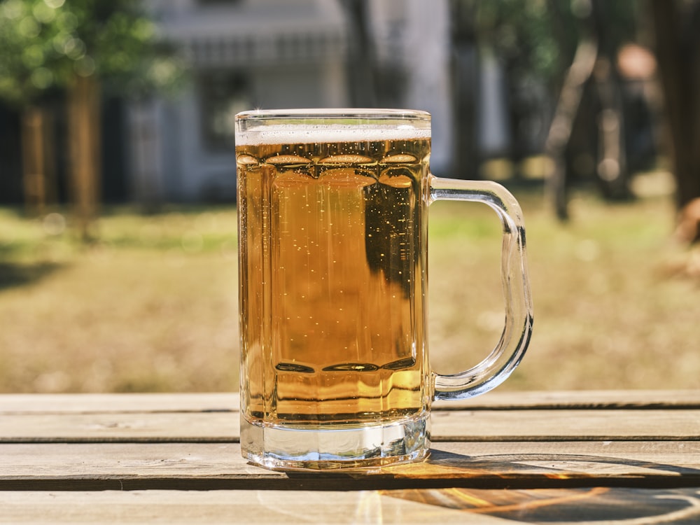 a glass of beer sitting on top of a wooden table