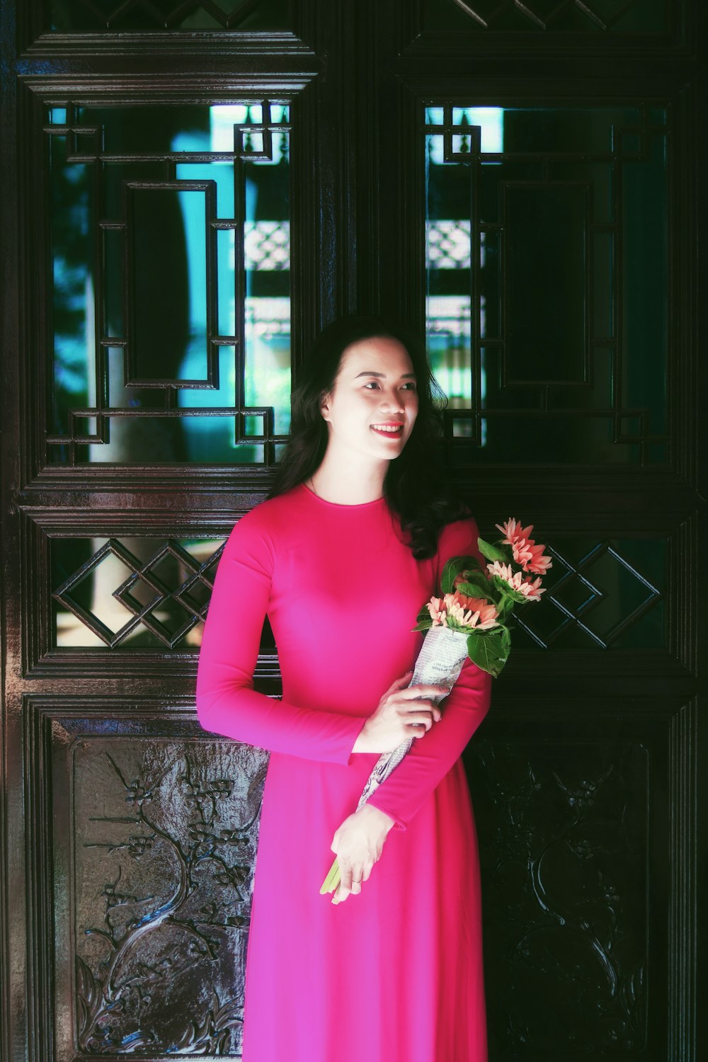 a woman in a pink dress holding a bouquet of flowers