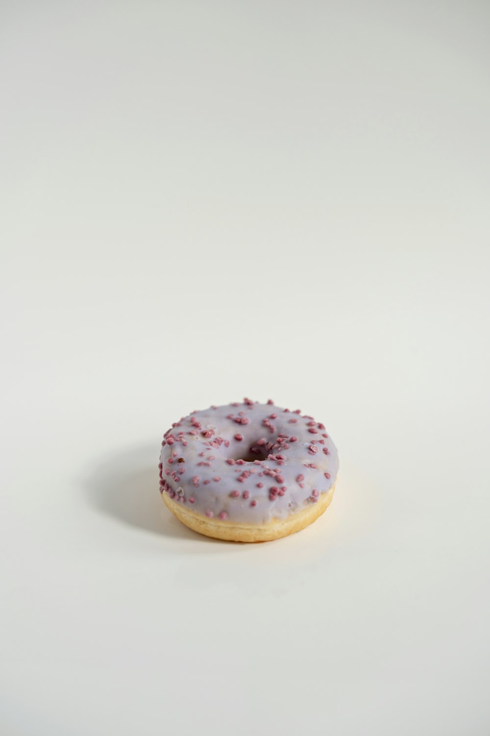 a white frosted donut with red sprinkles