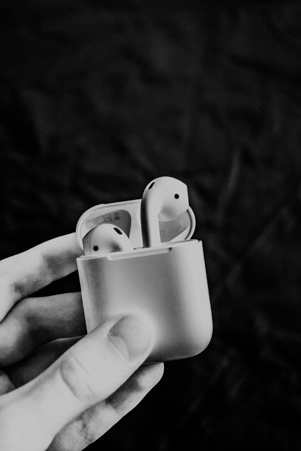 a hand holding an apple airpods in a cup