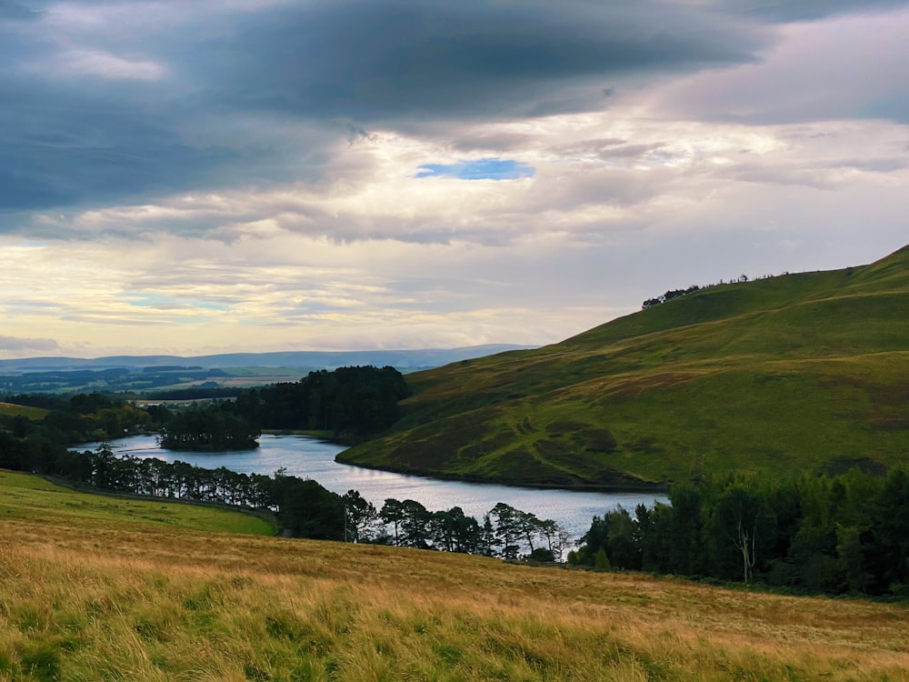 a grassy field with a river in the distance