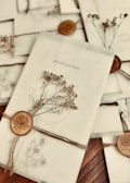 A collection of elegantly wrapped envelopes tied with twine and adorned with dried flowers and wax seals featuring a rose design. The envelopes are arranged casually on a wooden surface, creating a vintage and romantic ambiance.
