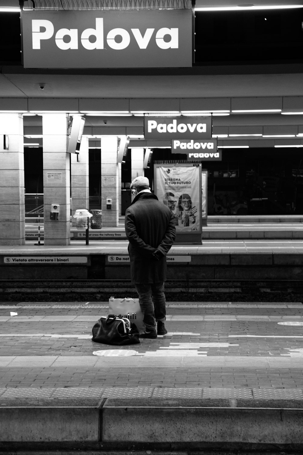 Un uomo in attesa di un treno in una stazione ferroviaria