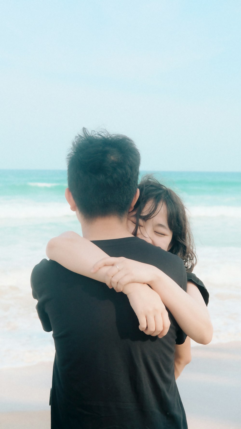 a man and a woman hug on the beach