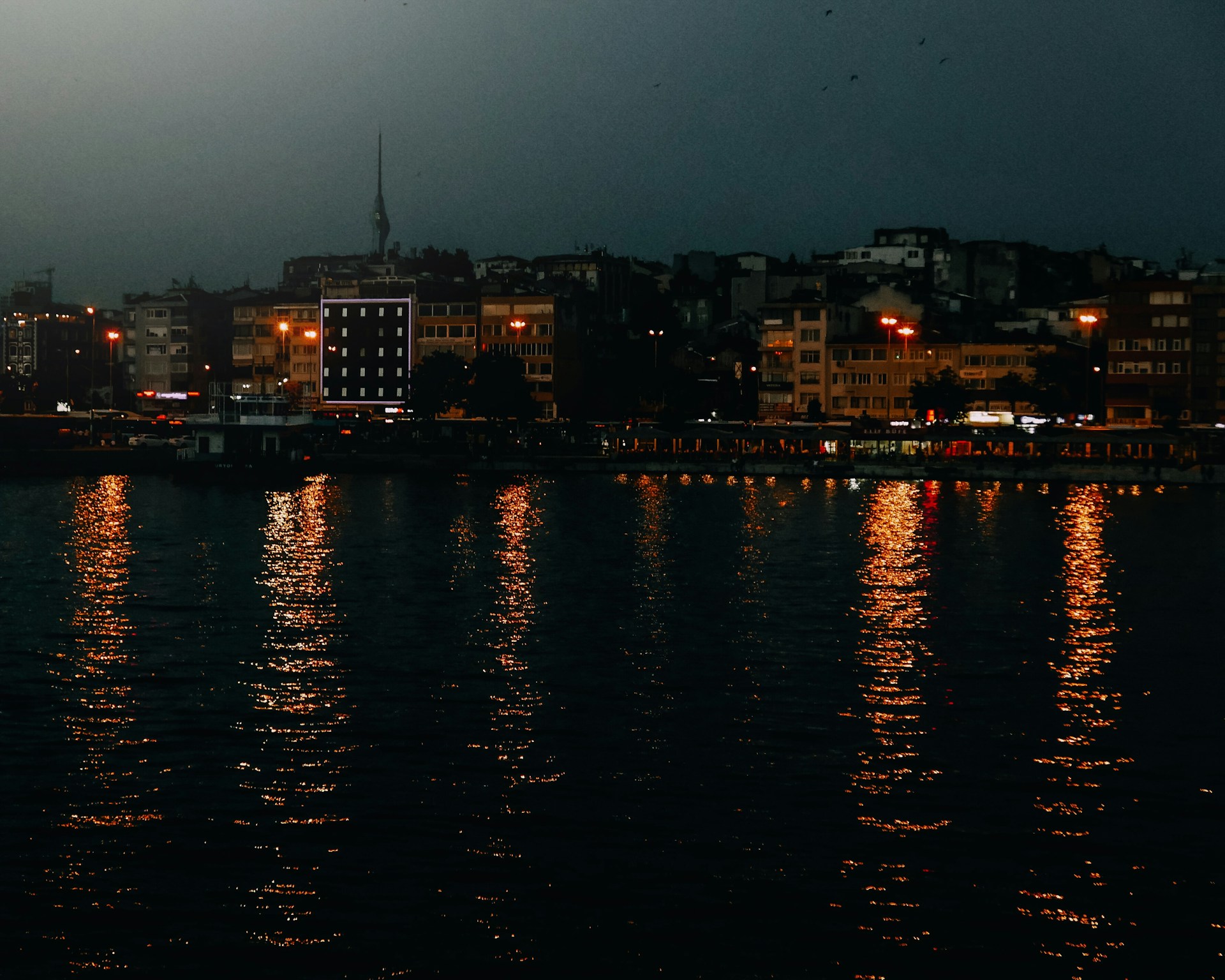 An atmospheric photo of a city square at dusk, with warm lights glowing from surrounding buildings.
