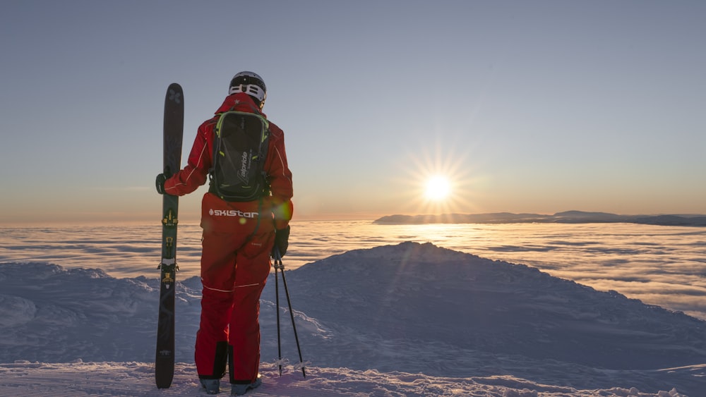 a man holding skis standing on top of a snow covered slope