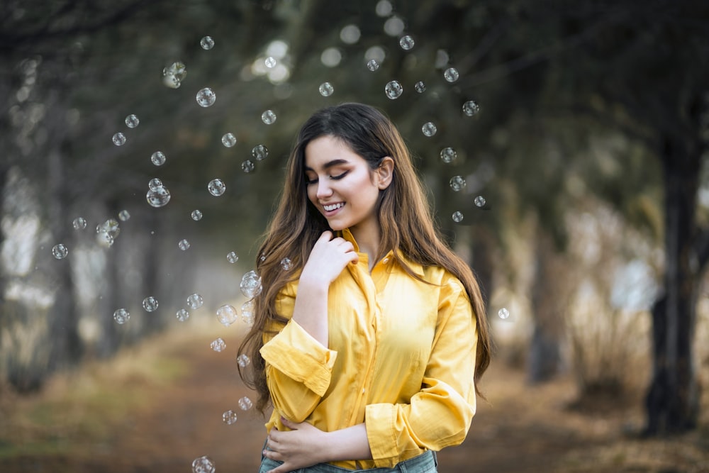 a woman in a yellow shirt is blowing bubbles