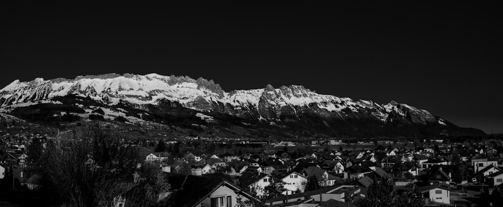 a black and white photo of a town with mountains in the background