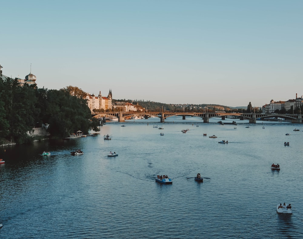 a group of boats floating down a river next to a bridge